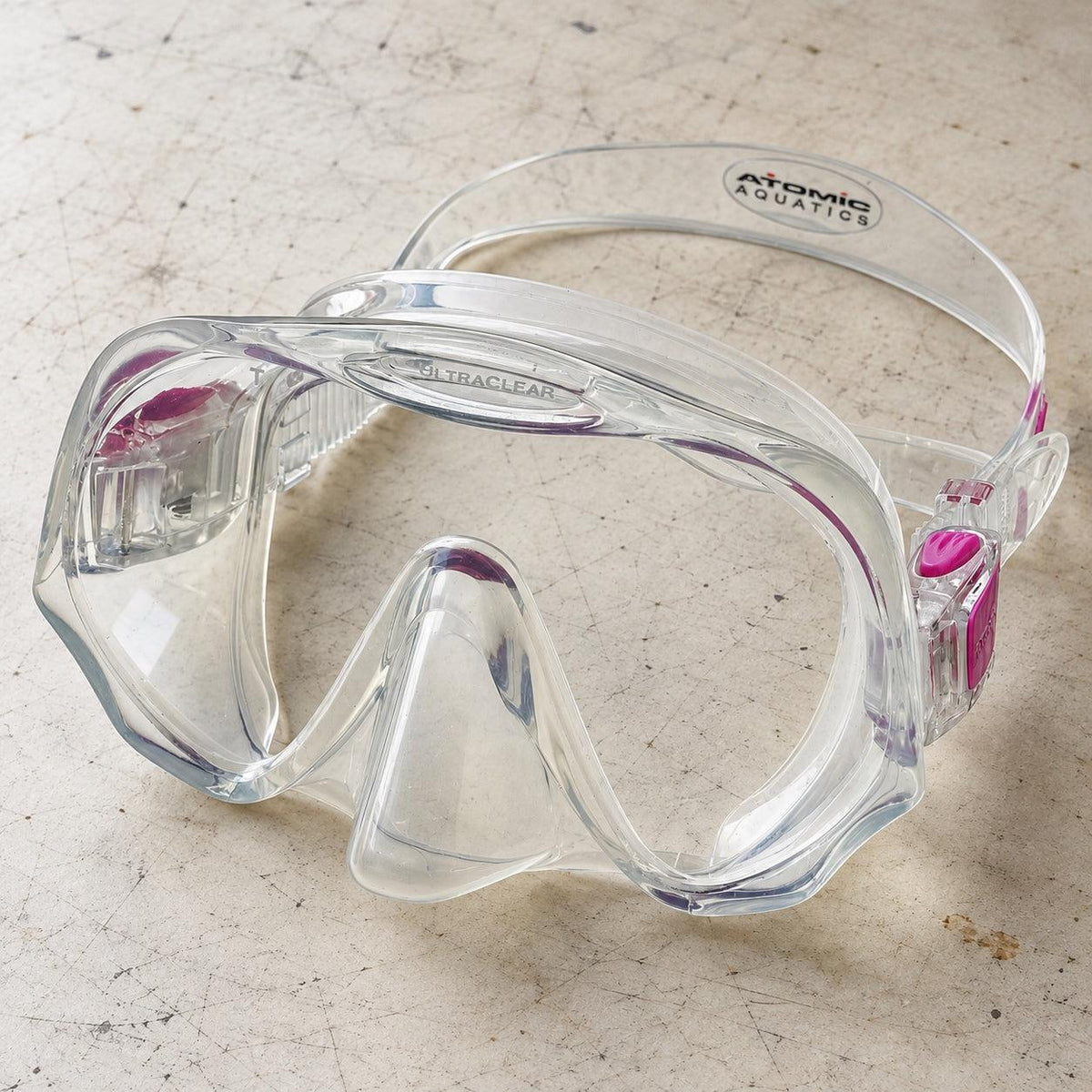 Open Box Atomic Aquatics Frameless Mask — Clear/Pink, open box, lightly used on off-white work table