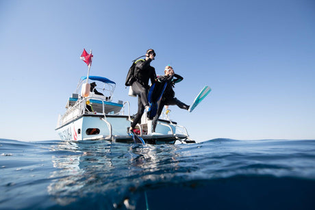 Divers giant-striding off a boat, returning to the water after time away from scuba diving