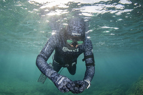 Spearfisher wearing a camouflage two-piece open cell freediving wetsuit underwater