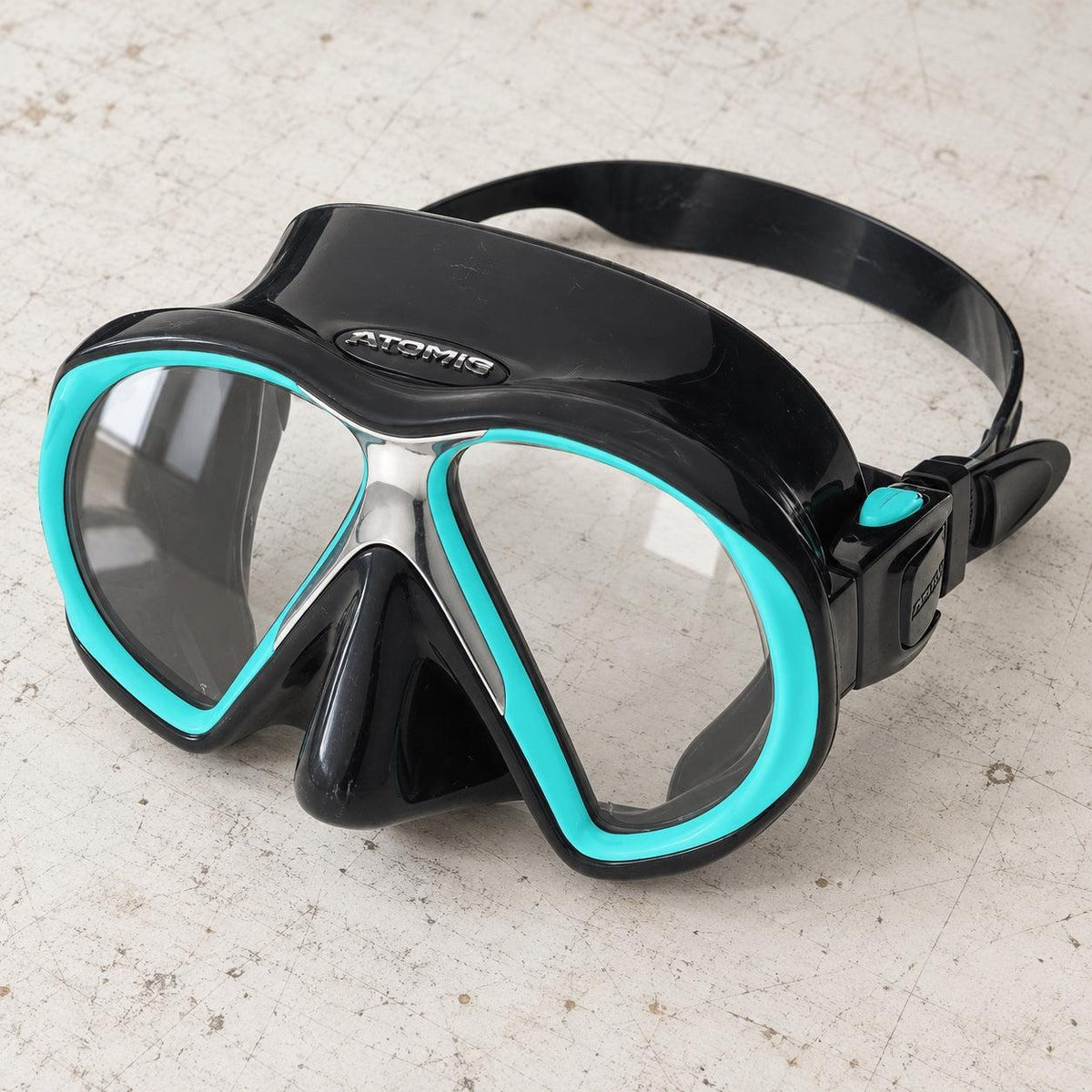 Open Box Atomic Aquatics SubFrame Mask — Black/Aqua, open box, lightly used on off-white work table