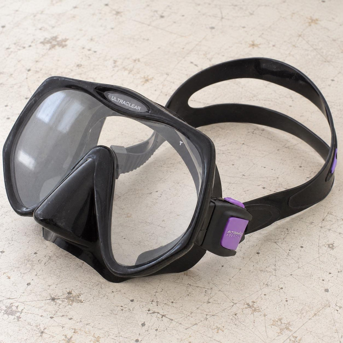 Open Box Atomic Aquatics Frameless Mask — Black/Purple, open box, lightly used on off-white work table