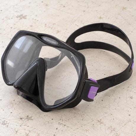 Open Box Atomic Aquatics Frameless Mask — Black/Purple, open box, lightly used on off-white work table